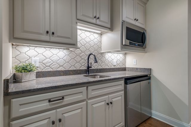 a kitchen with stainless steel appliances granite countertop white cabinets and a microwave oven