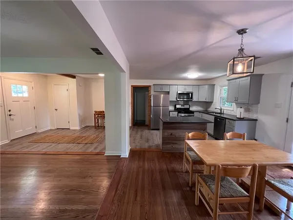 a kitchen with stainless steel appliances granite countertop a refrigerator a stove top oven a sink dishwasher and white cabinets with wooden floor