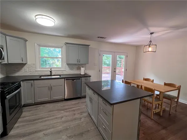a kitchen with granite countertop a stove two sinks a dining table and chairs