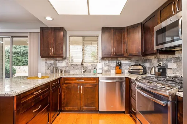 a kitchen with stainless steel appliances granite countertop a sink stove and microwave
