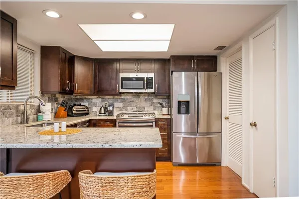 a kitchen with stainless steel appliances granite countertop a refrigerator a stove a sink a microwave and a refrigerator