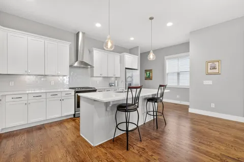 a kitchen with a dining table chairs wooden floors and white cabinets