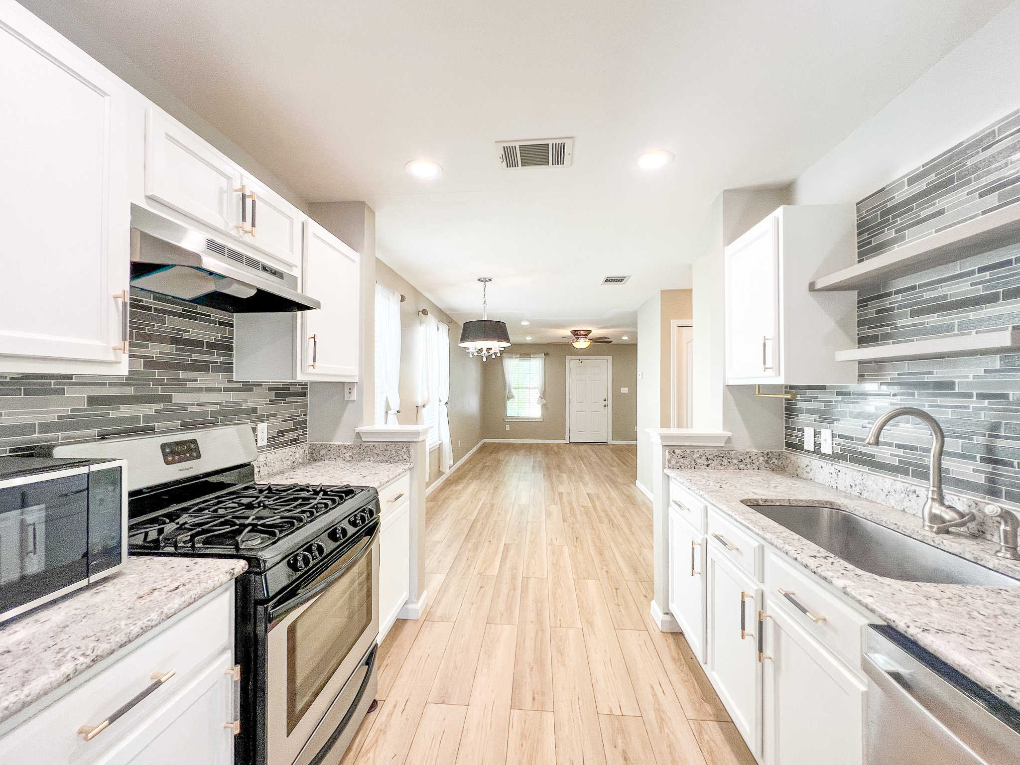 298 Jack Rabbit Lane Buda, TX 78610 - Photo 7 of 24 A streamlined kitchen features modern appliances, granite counters, and light wood flooring.