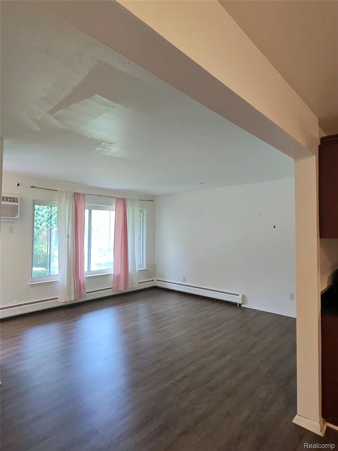 25301 Five Mile Road, Unit 130 Redford, MI 48239 - Photo 3 of 15 Open-concept living area with dark wood-finish flooring, white walls, and bright window light