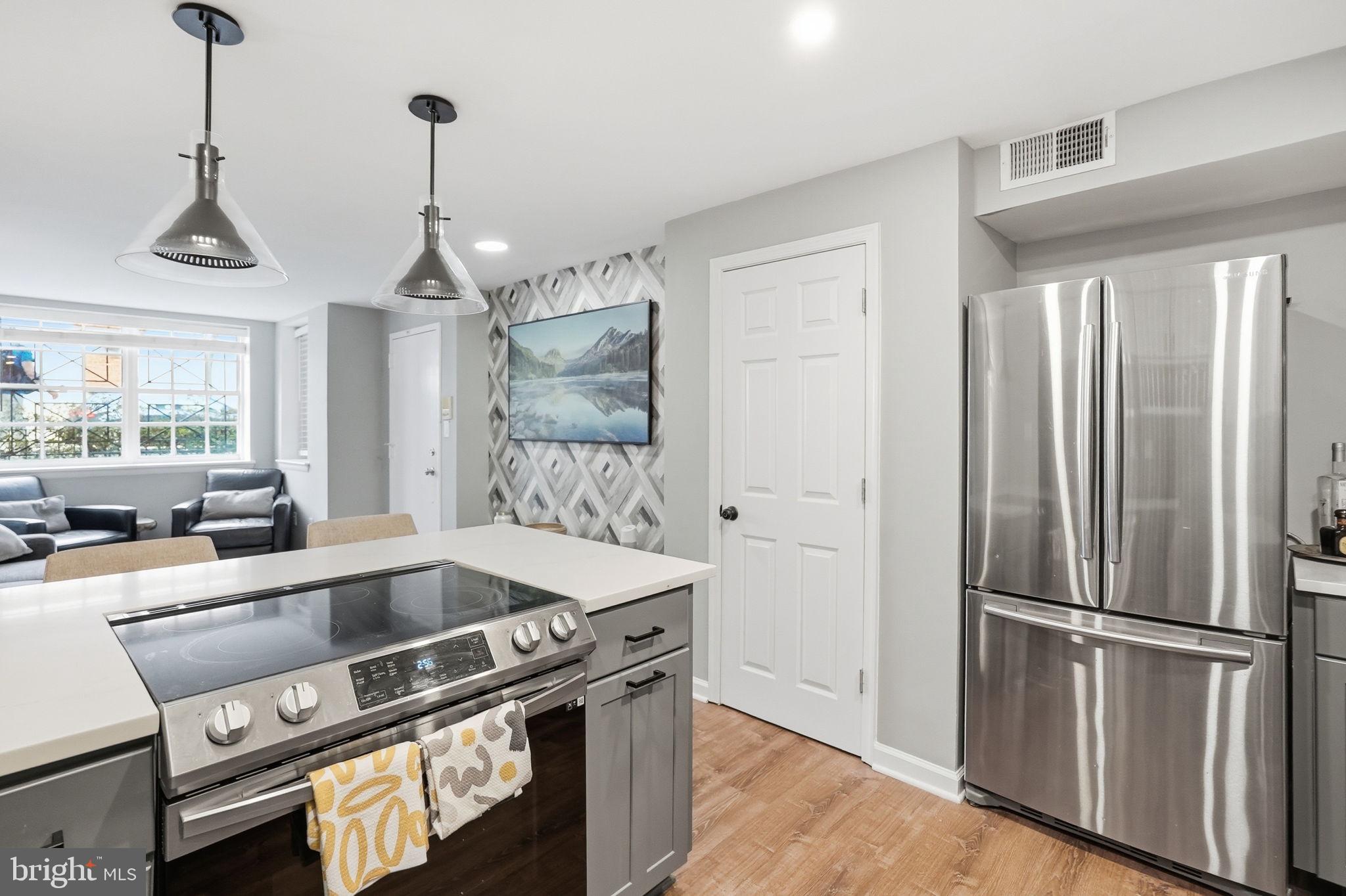 1712 Corcoran Street Northwest, Unit 2 Washington, DC 20009 - Photo 11 of 24 a kitchen with stainless steel appliances granite countertop a refrigerator a stove and a sink with wooden floor