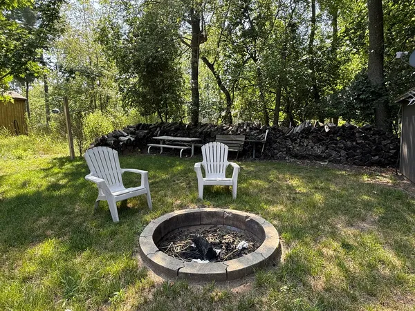 a view of a backyard with table and chairs potted plants and large tree