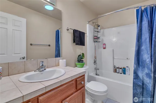 a bathroom with a granite countertop sink a toilet a mirror and shower