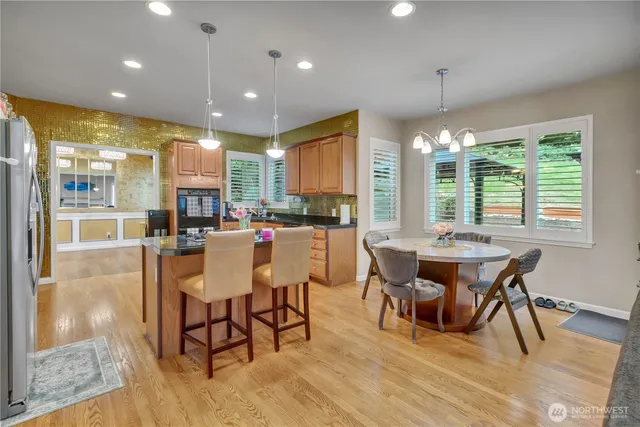 a dining room with stainless steel appliances granite countertop a table chairs and a view of living room