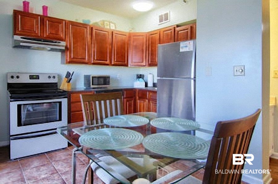 375 Plantation Road, Unit 5105 Gulf Shores, AL 36542 - Photo 6 of 9 Kitchen featuring wood-finish cabinetry, stainless steel appliances, and tile flooring