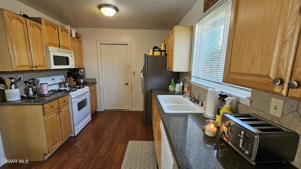 1542 Cochran Street Simi Valley, CA 93065 - Photo 3 of 5 a kitchen with stainless steel appliances a stove a sink a refrigerator white cabinets and wooden floor