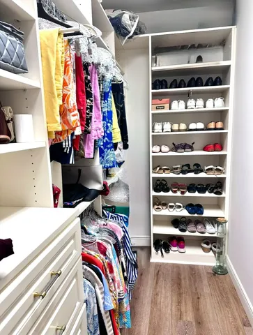 a view of walk in closet with clothes and shoes