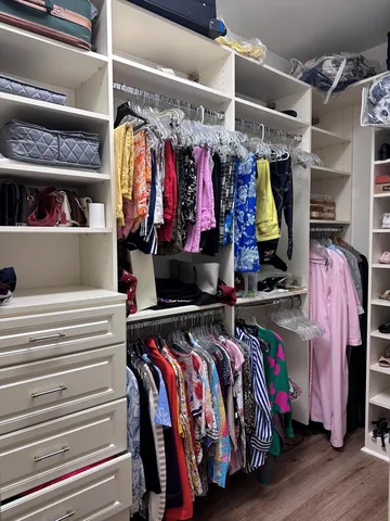 a view of walk in closet with clothes and shoes
