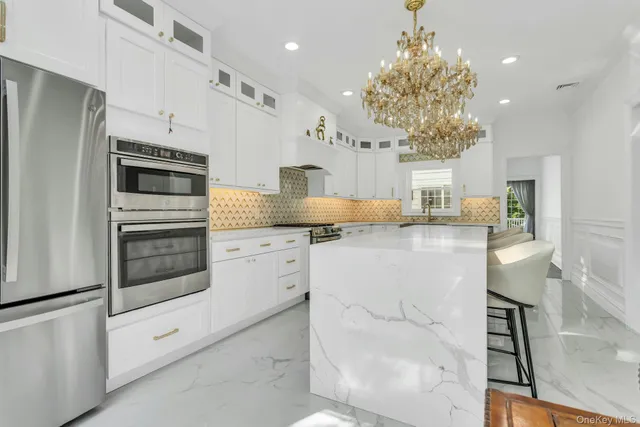 a kitchen with kitchen island granite countertop a refrigerator oven a sink dishwasher and white cabinets next to a window