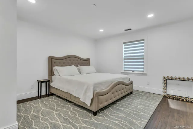 a large white bed sitting in a room next to a lamp