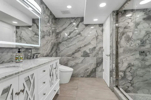 a bathroom with a granite countertop sink a toilet a mirror and shower