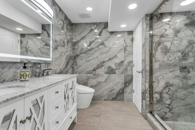a bathroom with a granite countertop sink a toilet a mirror and shower