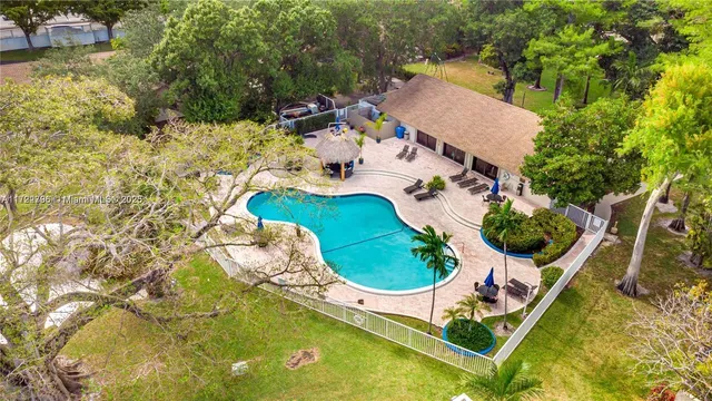 an aerial view of a swimming pool with outdoor seating and yard