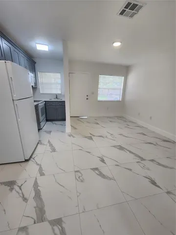 a view of kitchen with refrigerator and white cabinets