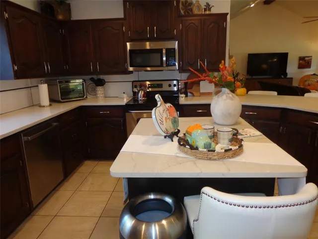 a kitchen with stainless steel appliances granite countertop a sink a stove a microwave a refrigerator and cabinets