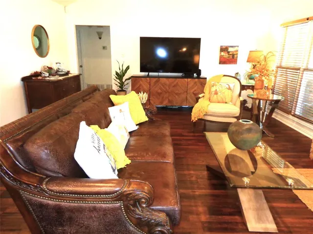 a living room with couches and a flat screen tv with kitchen view