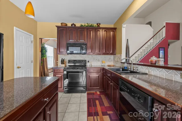 a kitchen with stainless steel appliances granite countertop a sink a stove and a refrigerator