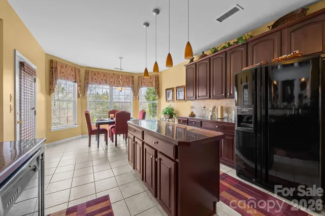 a kitchen with stainless steel appliances granite countertop a refrigerator a sink a stove and a dining table with wooden floor