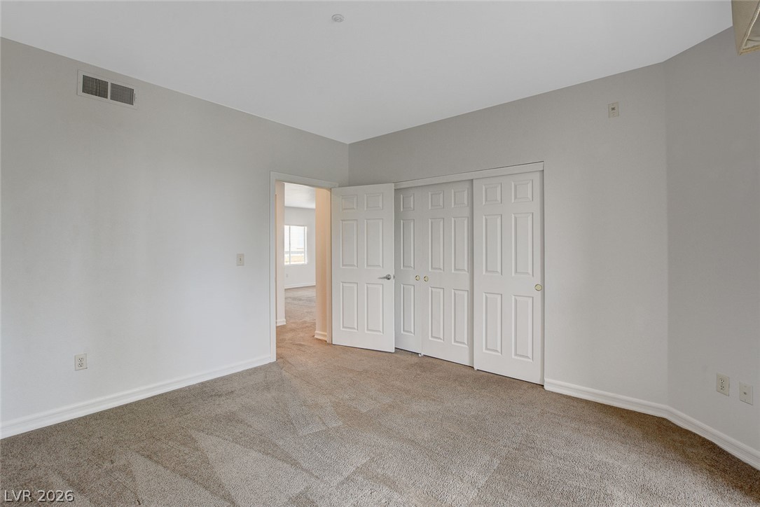 230 East Flamingo Road, Unit 404 Las Vegas, NV 89169 - Photo 25 of 34 Plush carpeting anchors this spacious bedroom featuring a wall of closet storage.