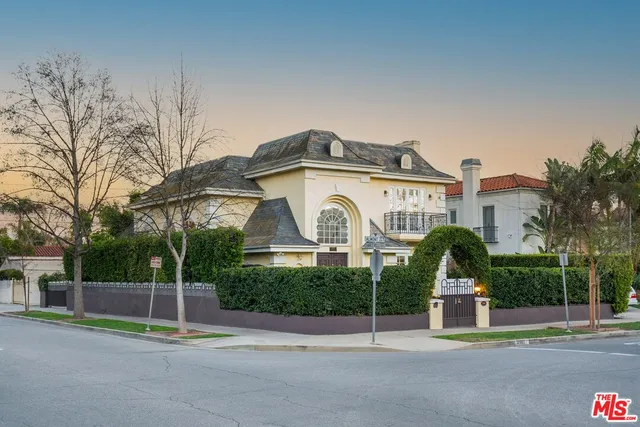 a view of a white house with a small yard and palm trees