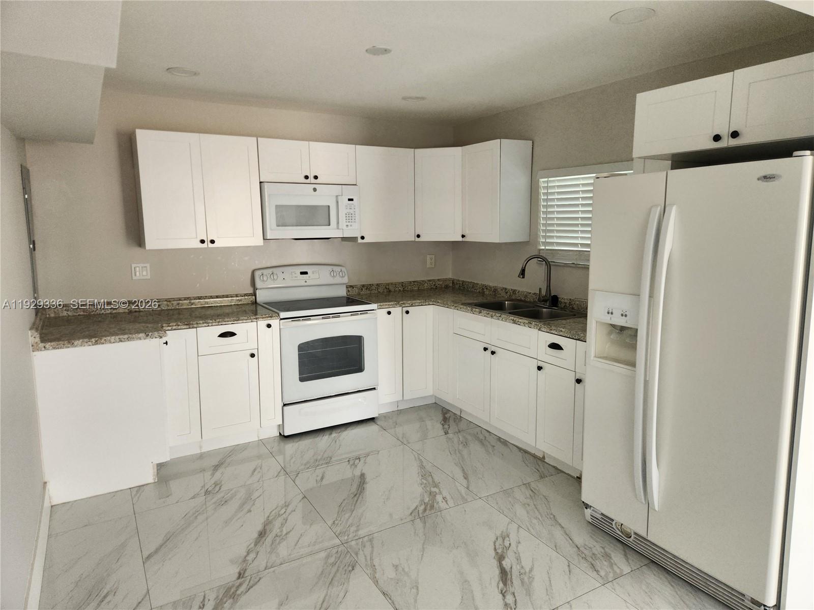 342 East 46th Street, Unit 1 Hialeah, FL 33013 - Photo 4 of 26 a kitchen with granite countertop white cabinets and white appliances
