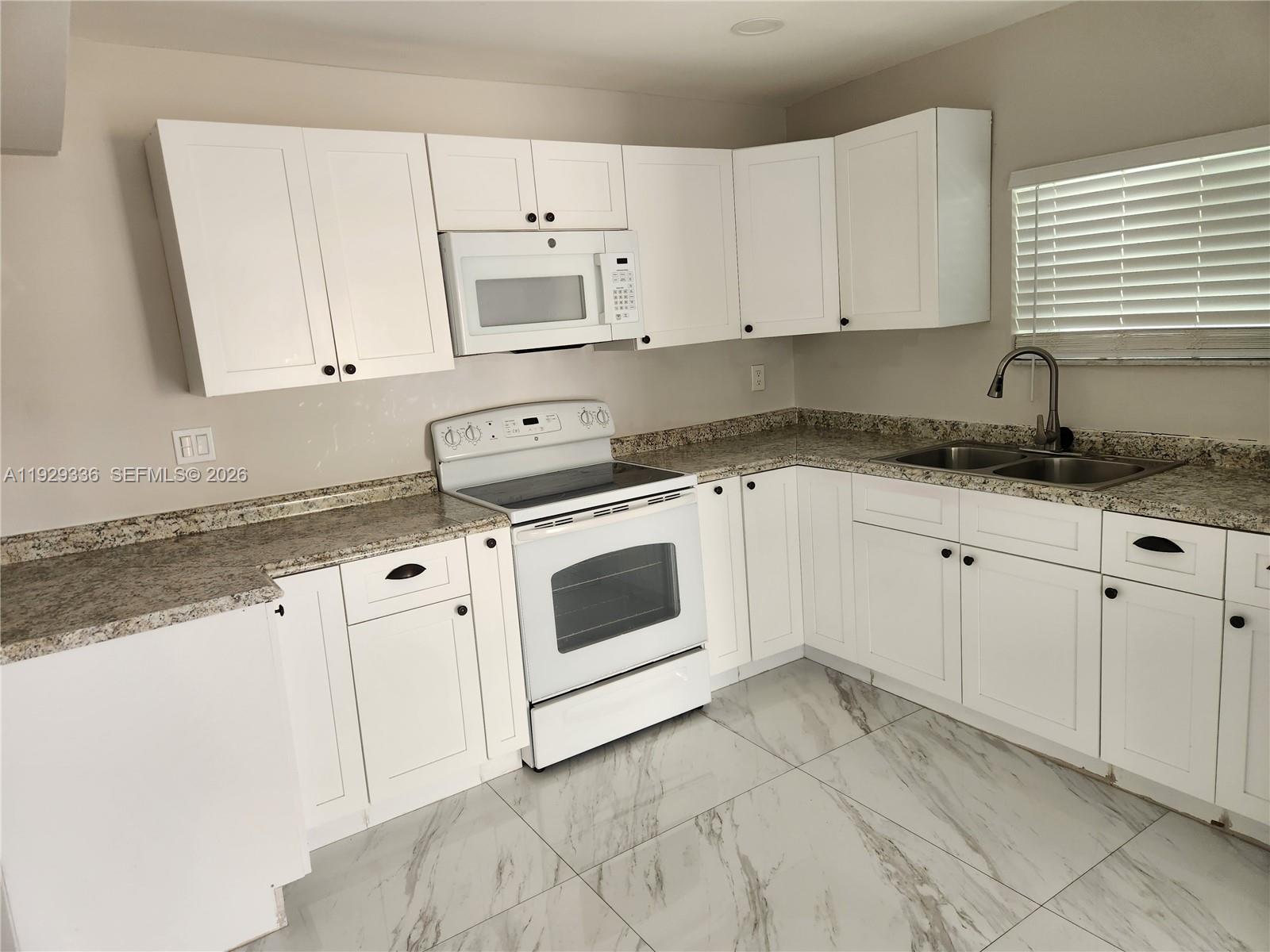 342 East 46th Street, Unit 1 Hialeah, FL 33013 - Photo 5 of 26 a kitchen with granite countertop white cabinets and white appliances
