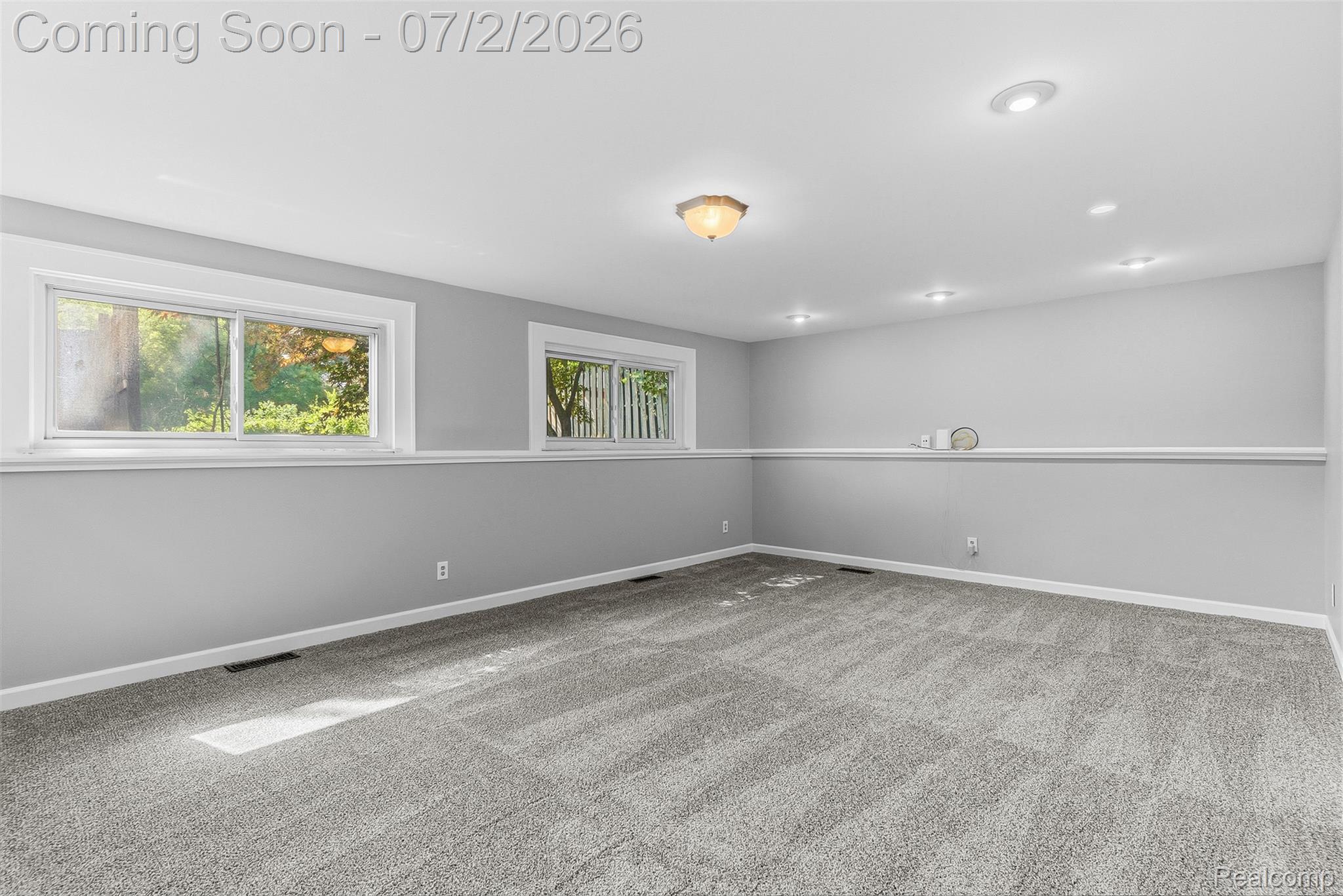 305 East Road Holly, MI 48442 - Photo 23 of 41 Spacious room featuring light gray walls, white trim, two windows, recessed lighting, and a neutral carpeted floor