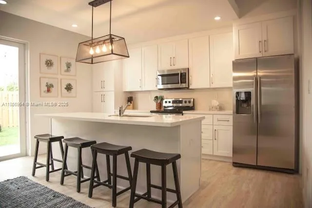 a kitchen with stainless steel appliances granite countertop a refrigerator a stove a microwave oven a sink with island chairs and wooden floor