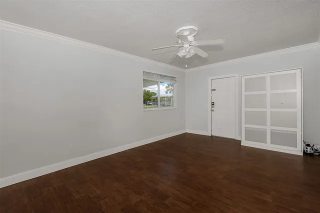 an empty room with wooden floor closet and windows