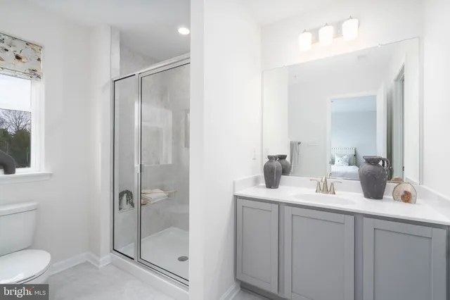 a bathroom with a shower sink vanity mirror and toilet