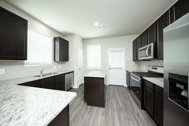 a kitchen with stainless steel appliances kitchen island granite countertop a stove a sink and a microwave