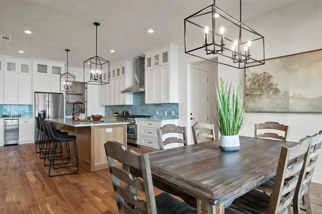 a open kitchen with stainless steel appliances granite countertop a stove a kitchen island a table and chairs in it