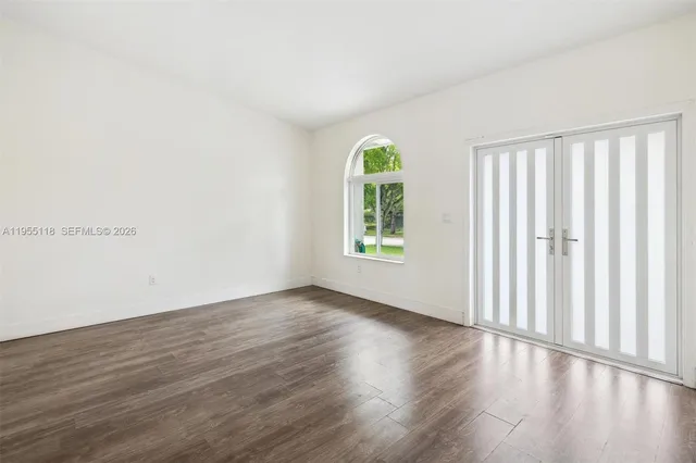 an empty room with wooden floor and windows