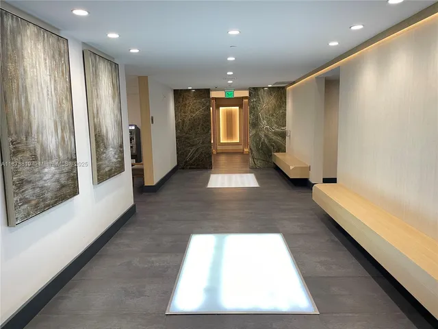 a view of hallway with stainless steel appliances a refrigerator and cabinets