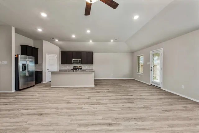 a view of kitchen with stainless steel appliances kitchen island empty cabinets and wooden floor
