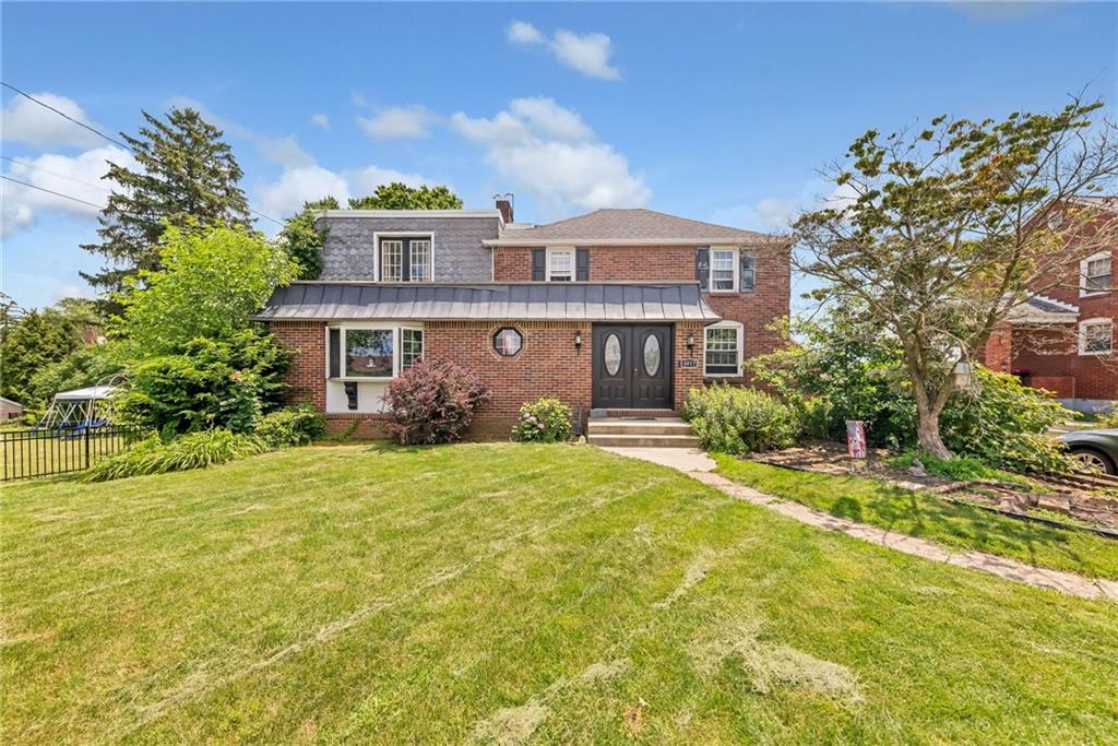 a front view of a house with a yard and trees