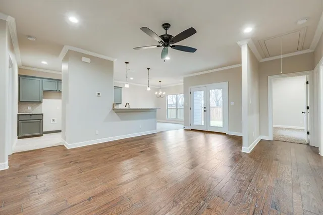 a view of an empty room with wooden floor and a ceiling fan