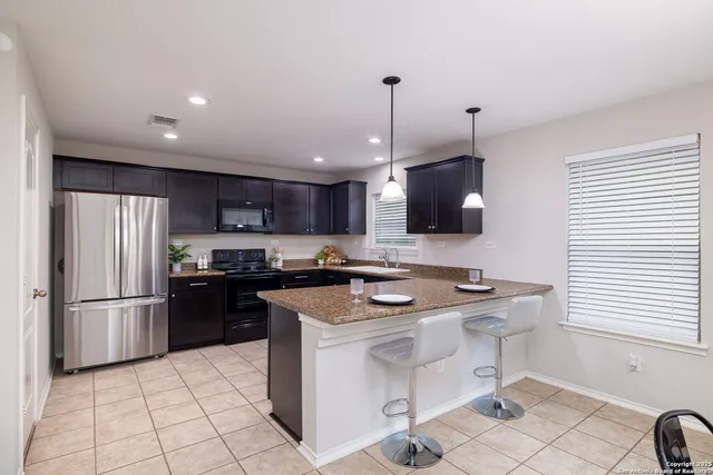 a kitchen with stainless steel appliances granite countertop a sink a stove a refrigerator and a refrigerator
