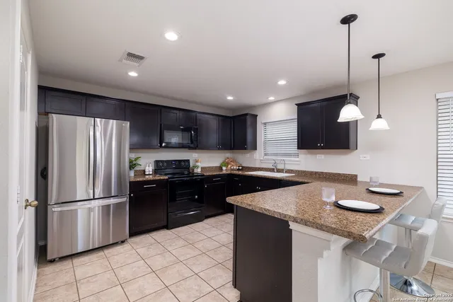 a kitchen with granite countertop kitchen island stainless steel appliances a refrigerator a sink a stove a microwave and island