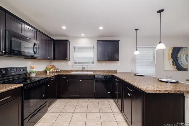 a kitchen with stainless steel appliances granite countertop a sink a stove and a wooden cabinets