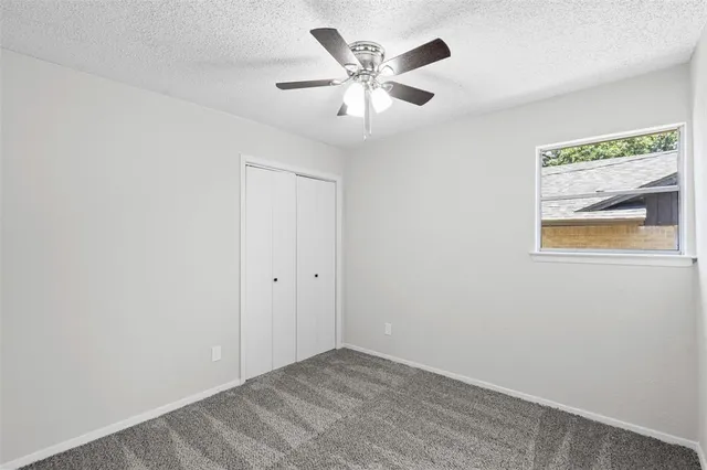 an empty room with ceiling fan and window