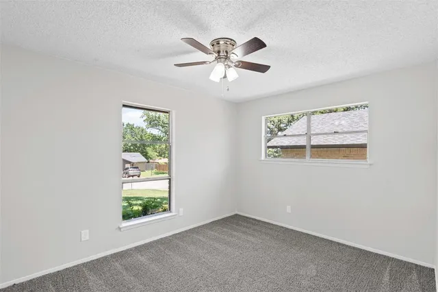 an empty room with windows and fan