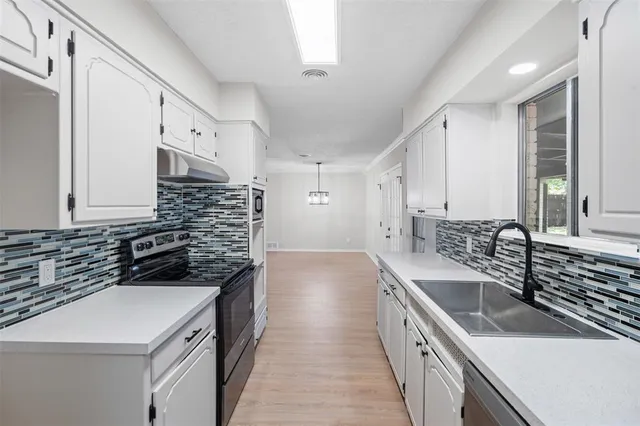 a kitchen with a sink stove top oven and cabinets