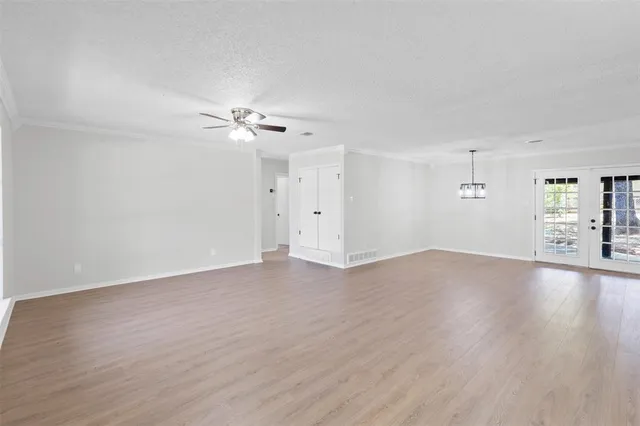 a view of an empty room with window and wooden floor