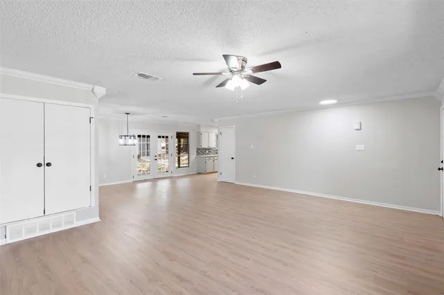 a view of empty room with wooden floor and ceiling fan