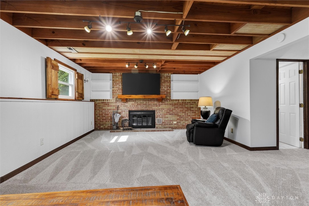 2165 Stewart Road Xenia, OH 45385 - Photo 19 of 59 This finished basement offers an inviting space for relaxation and entertainment, complete with exposed beams and a cozy fireplace.